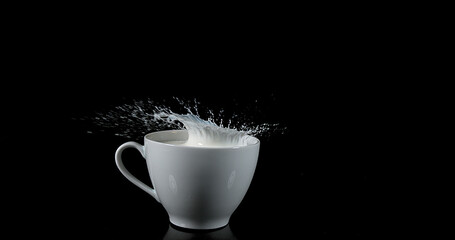 Bowl with Exploding Milk against Black Background