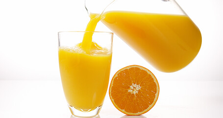 Orange Juice being poured into Glass against White Background