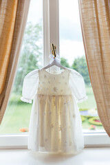 White dress on cute hanger. Set of white baby clothes for wedding. Fashion childs outfit. Little white dress for kids bridesmaid. Wedding photography. 