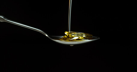 Olive Oil, Falling in a Spoon against Black Background