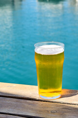 Pint of golden colour lager beer in a waterfront bar overlooking a marina. No people.