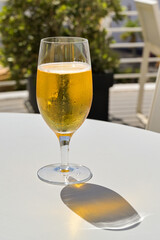 Glass of cold golden colour lager beer on a table on the outdoor terrace of a hotel bar. No people.