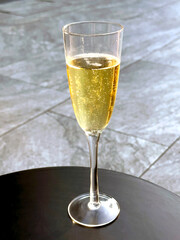 Glass of prosecco on a table on a garden patio. No people.