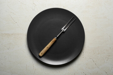 Meat fork in a black plate.