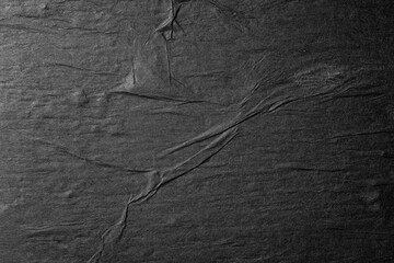 Black paper background with folds close up.