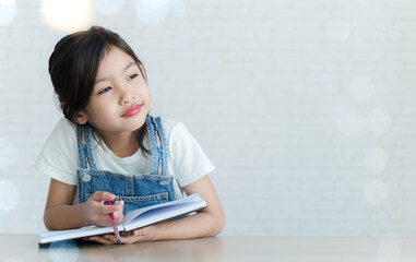 The girl is reading a book and writing a diary and having fun.