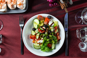 Greek salad of fresh cucumber, tomato, sweet pepper, lettuce,feta cheese, olives and balsamic vinegar in plate.