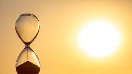 Hourglass counts the length of time against the background of the evening sun. The concept of the...