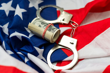 United States of America flag with handcuffs and a bundle of dollars. Currency corruption in the country. Financial crimes