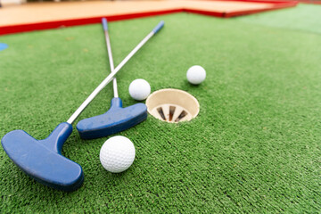 Fun vacation entertainment for summertime. Playing mini golf on green grass outdoors. Setting goals and winning lifestyle concept. Competition at golf course: two crossed sticks. Blank space for copy.