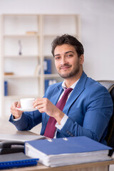 Young male employee drinking coffee during break