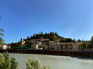 Houses in front of a hill and with the river Adige in the foreground in Verona