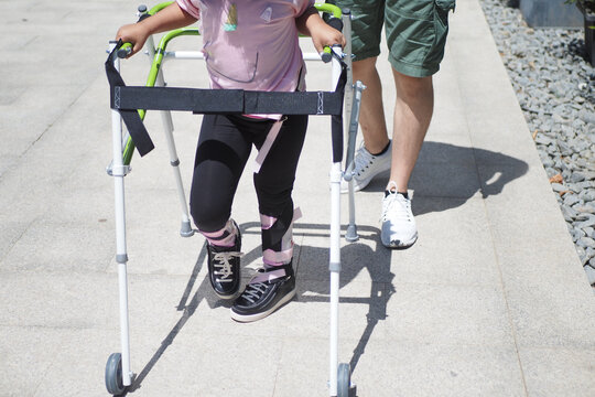  child with walking frame and knee orthosis outdoor 