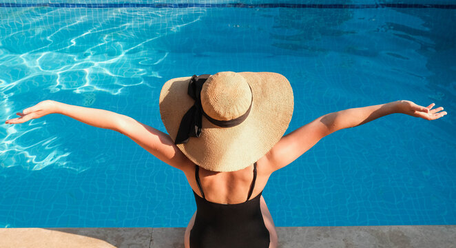Happy woman with hat enjoys her vacation in the pool