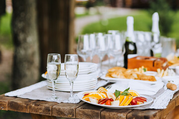 A round fruit plate, champagne glasses stand on a wooden table at a banquet. Photo of food, dessert, buffet at the holiday.