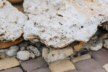 An old uneven decorative mountain stone, a cobblestone in holes lies on a tile. Photography, nature, background.