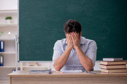 Young male teacher in front of green board