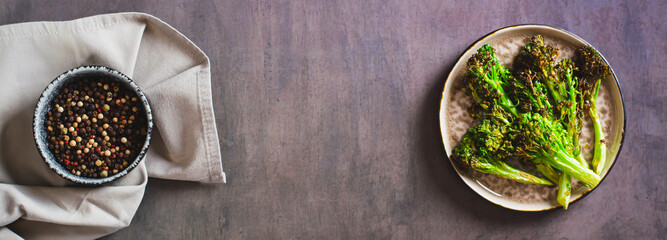 Roasted fresh broccoli sprouts in oil on a plate on the table top view web banner