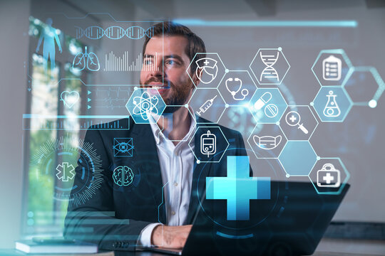 Smiling businessman in formal wear working on laptop at office workplace with smartphone and notebooks. Concept of successful business deal, agreement. Medical healthcare icons.