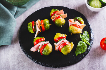 Appetizing sliders with vegetables and ham on a slate board