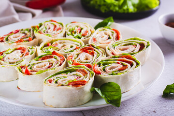 Italian rolled sandwiches with lettuce, ham and baked peppers in pita bread on a plate