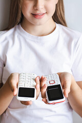 Two white old-fashioned push-button telephones in the hands of a girl vertical view