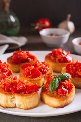 Appetizing crostini on bread with fried tomatoes and garlic on a plate vertical view