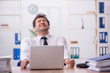 Obraz premium Young male employee and too much work in the office