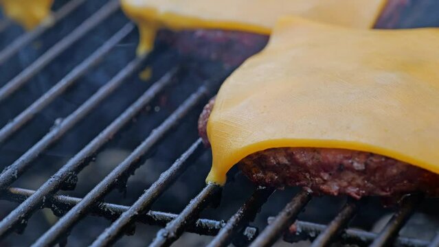Cheese burgers grilling on a bbq with cheese melting 
