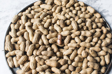 Top view of shelled groundnut in a large tray, flatlay of shelled peanut in a tray on a marble countertop