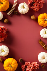 Fototapeta premium Autumn, fall vertical banner design with ripe pumpkins, flowers, cinnamon sticks, walnuts, pine cones on dark red background.