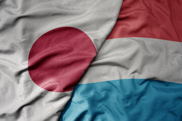 big waving national colorful flag of japan and national flag of luxembourg .
