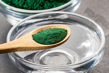 Spoon with organic spirulina powder and glass of filtered water