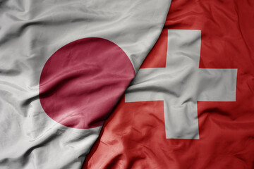 big waving national colorful flag of japan and national flag of switzerland .