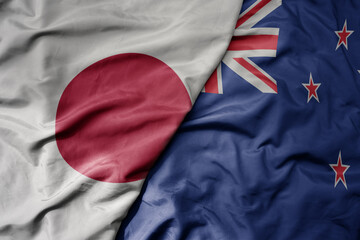 big waving national colorful flag of japan and national flag of new zealand .