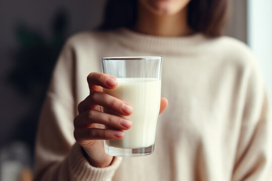 Woman is seen holding glass of milk in her hand. This image can be used to promote healthy lifestyle, dairy products, or as concept of nutrition and wellness.