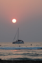 sailboat with pink sun at sunset