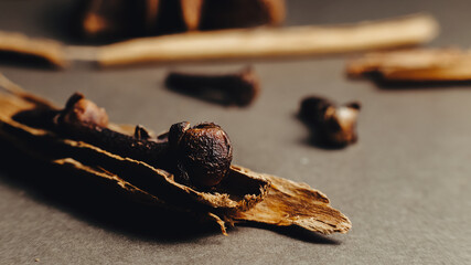 Close-up detail of cinnamon, clove, and star anise on a gray background. Selective focus, macro shot.