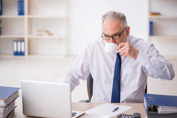 Fototapeta premium Old male employee drinking coffee during break