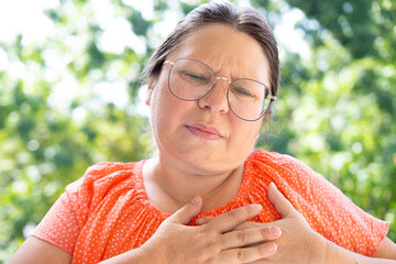 woman 40-45 years old holds on to heart, sudden chest pain, close up female face with facial...