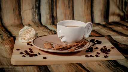 White cup of coffee with cookie and coffee beans on wooden background.
