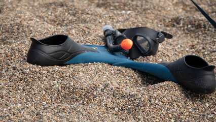 swim goggles and flippers on the sand at the seaside