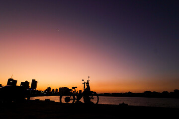 Campos dos Goytacazes, RJ, Brazil, 08/19/2023 - Woman and child with a bike in silhouette at sunset