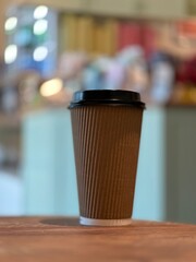 Closeup of isolated brown non branded hot coffee to go cup with a beautiful blue blurred background with bokeh 
