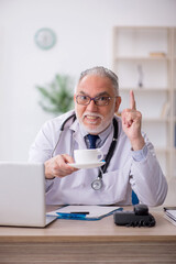 Fototapeta premium Old male doctor drinking coffee during break