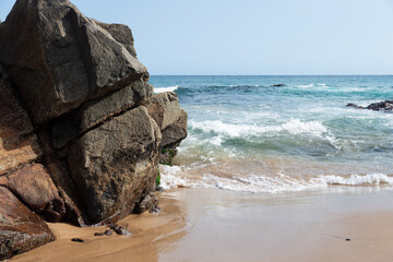 Fototapeta na wymiar Sea waves crashing on the black rocks of the beach.