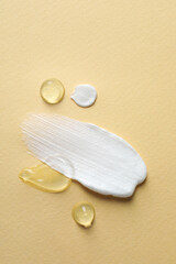Samples of transparent gel and white cream on yellow background, flat lay