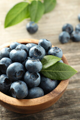 Bowl of tasty fresh blueberries on wooden table, closeup