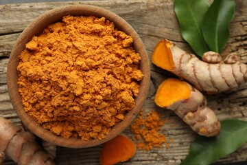 Aromatic turmeric powder and raw roots on wooden table, flat lay