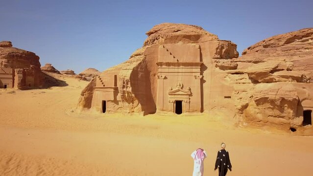 Saudi Arabia aerial view of a desert landscape in Al Ula with carved sandstone with temples and tombs with an european woman and saudi person visiting